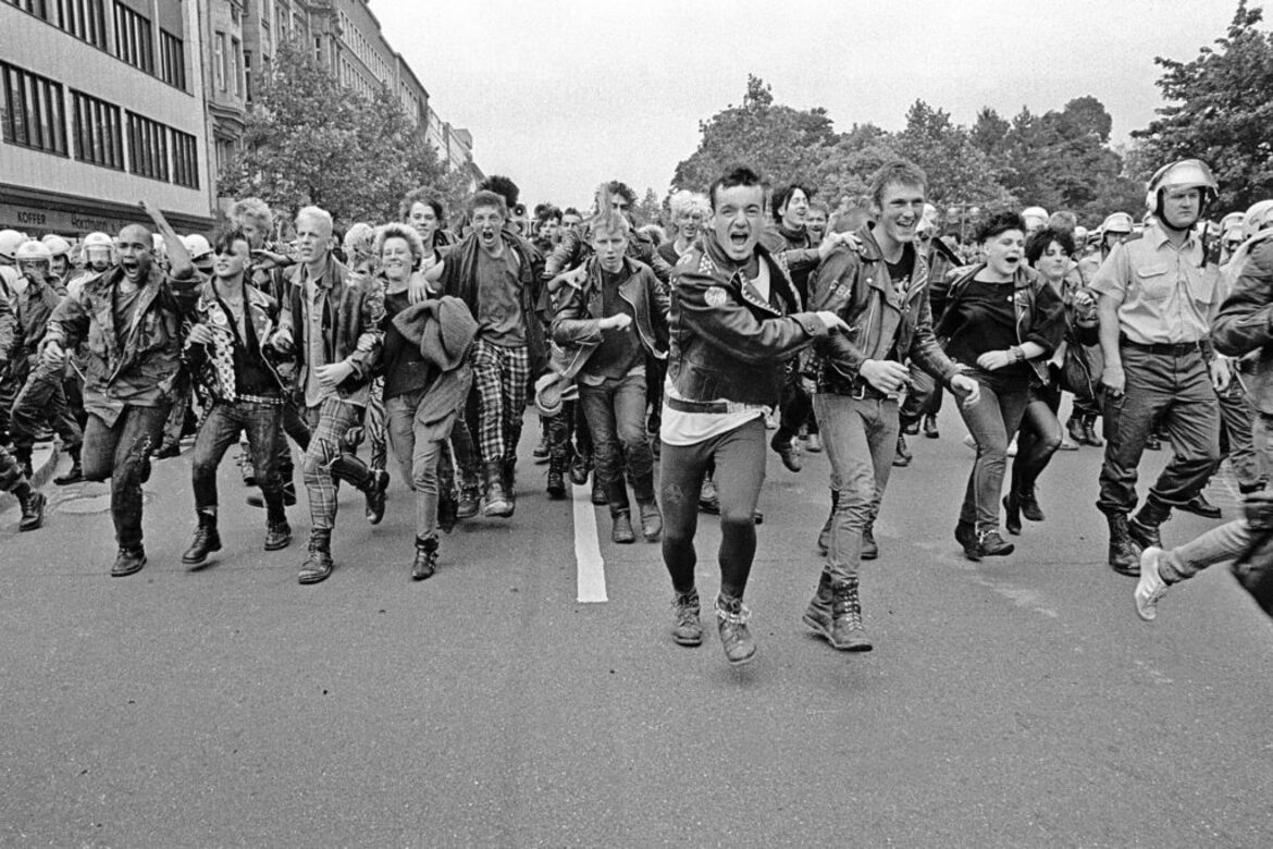 Zu sehen ist eine Gruppe von Menschen verschiedenen Alters. Sie laufen auf einer Straße auf den Fotografen zu. ©Deutsche Fotothek/Martin Langer 